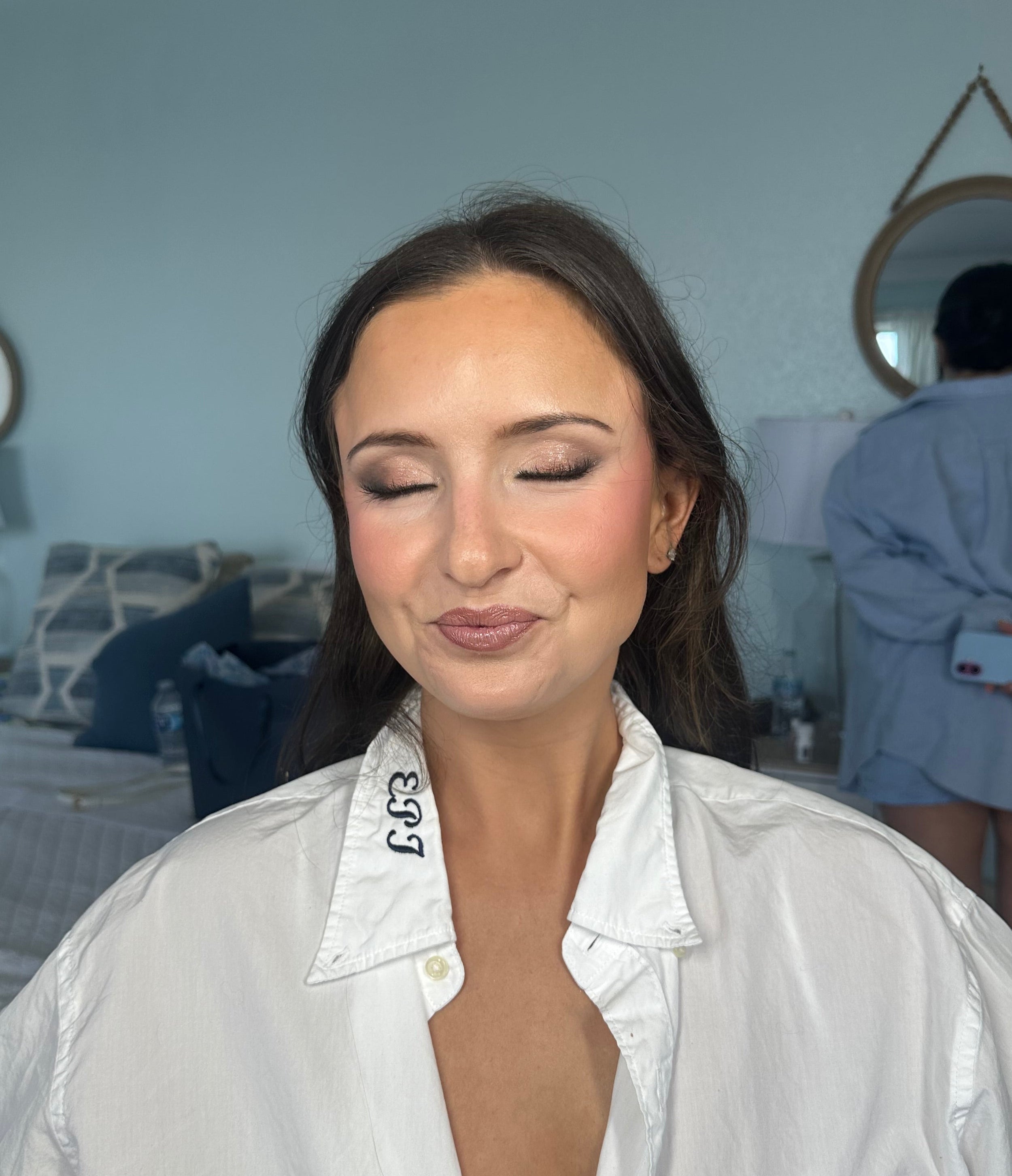 Bride wearing a white shirt with a brand logo in a bedroom setting